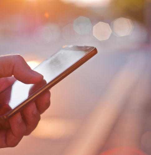 Man using mobile smartphone. Close up of a businessman hand holding and using a smart phone outdoors. Detail of handsome hipster modern businessman using smart phone in the city